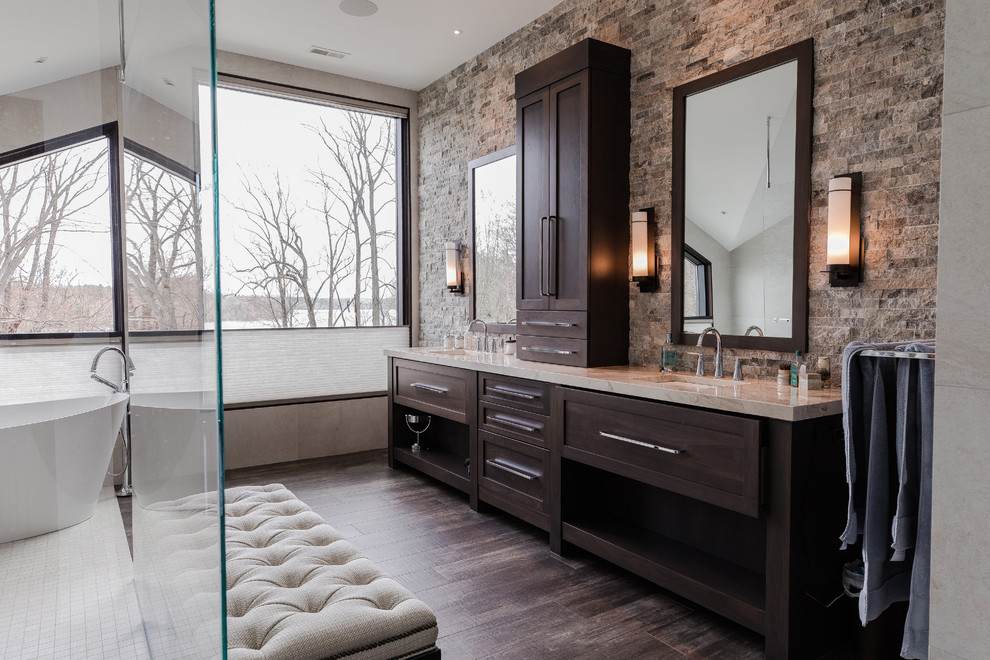 Photo of a transitional master bathroom in Other with shaker cabinets, dark wood cabinets, a freestanding tub, a curbless shower, brown tile, stone tile, beige walls, dark hardwood floors, an undermount sink, brown floor, an open shower and beige benchtops.