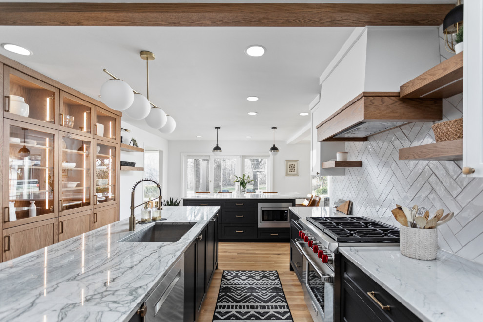 This is an example of a transitional u-shaped kitchen in Indianapolis with an undermount sink, shaker cabinets, black cabinets, white splashback, stainless steel appliances, light hardwood floors, beige floor and white benchtop.