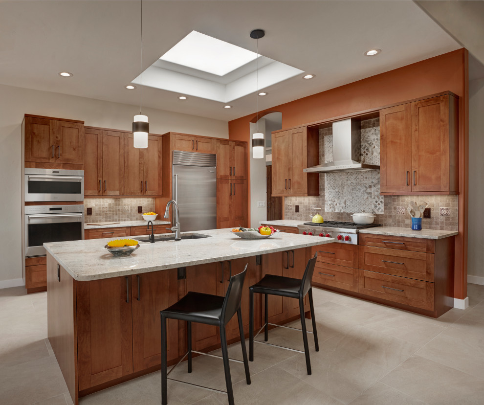 Example of a mid-sized transitional u-shaped travertine floor and beige floor eat-in kitchen design in Phoenix with shaker cabinets, medium tone wood cabinets, granite countertops, beige backsplash, porcelain backsplash, stainless steel appliances, an island and multicolored countertops