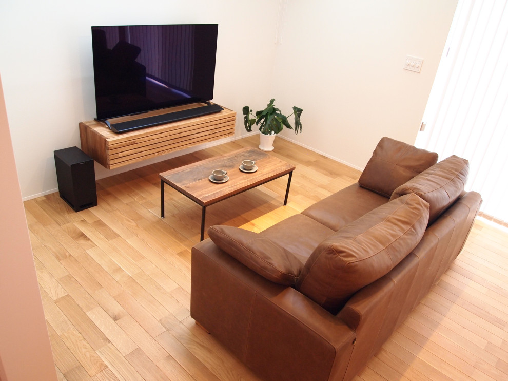 Exempel på ett mellanstort skandinaviskt allrum med öppen planlösning, med vita väggar, mellanmörkt trägolv, en fristående TV och brunt golv