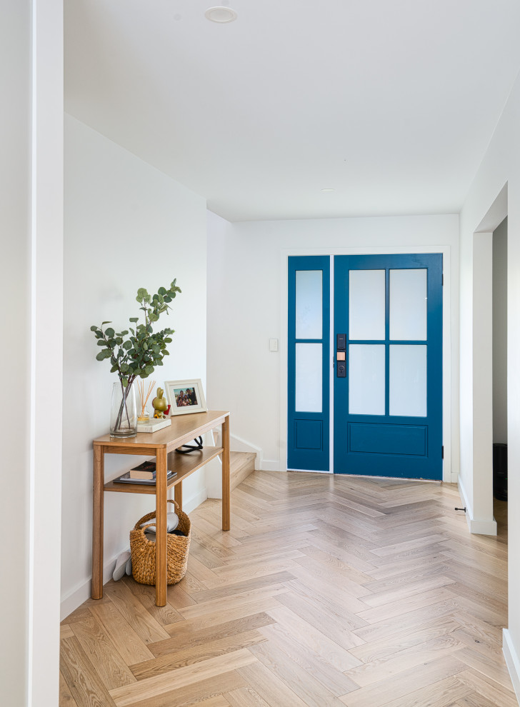 Aménagement d'une porte d'entrée contemporaine avec un mur blanc, parquet clair, une porte simple, une porte bleue et un sol beige.