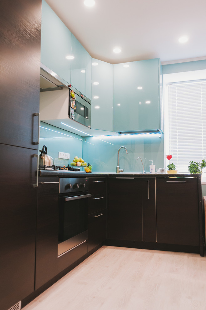 Photo of a mid-sized contemporary l-shaped eat-in kitchen in Other with a drop-in sink, turquoise cabinets, laminate benchtops, glass tile splashback, stainless steel appliances and laminate floors.