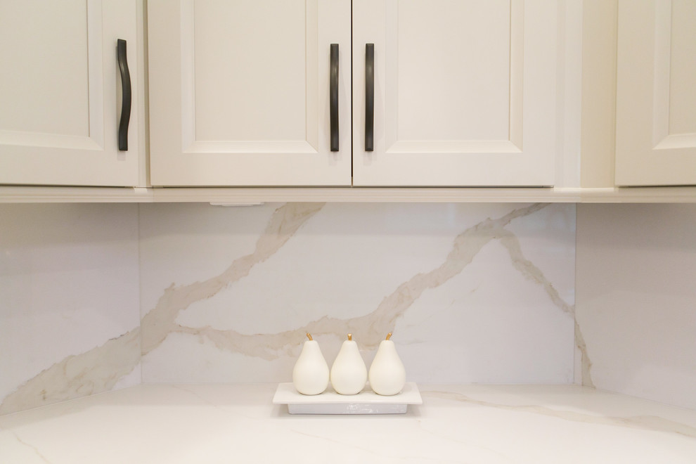 Example of a mid-sized transitional u-shaped open concept kitchen design in Orlando with recessed-panel cabinets, white cabinets, quartzite countertops, white backsplash, stone slab backsplash, stainless steel appliances and a peninsula