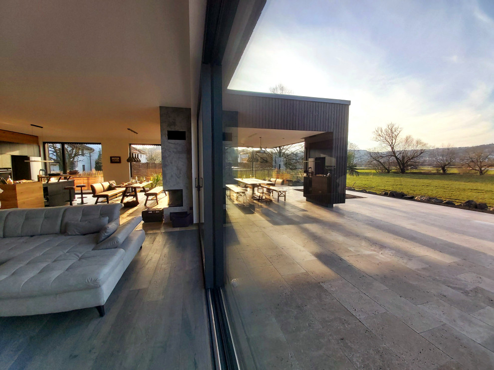 This is an example of a large contemporary ground level deck in Frankfurt with an outdoor kitchen and a roof extension.