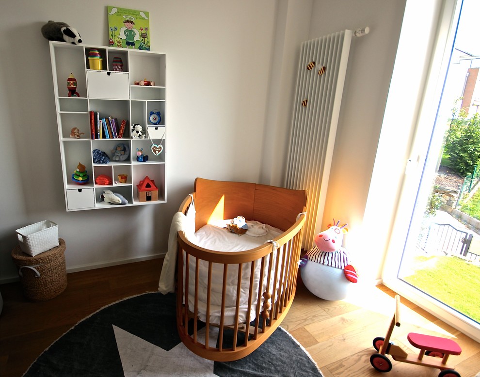 Mid-sized eclectic nursery in Frankfurt with white walls, light hardwood floors and brown floor for girls.