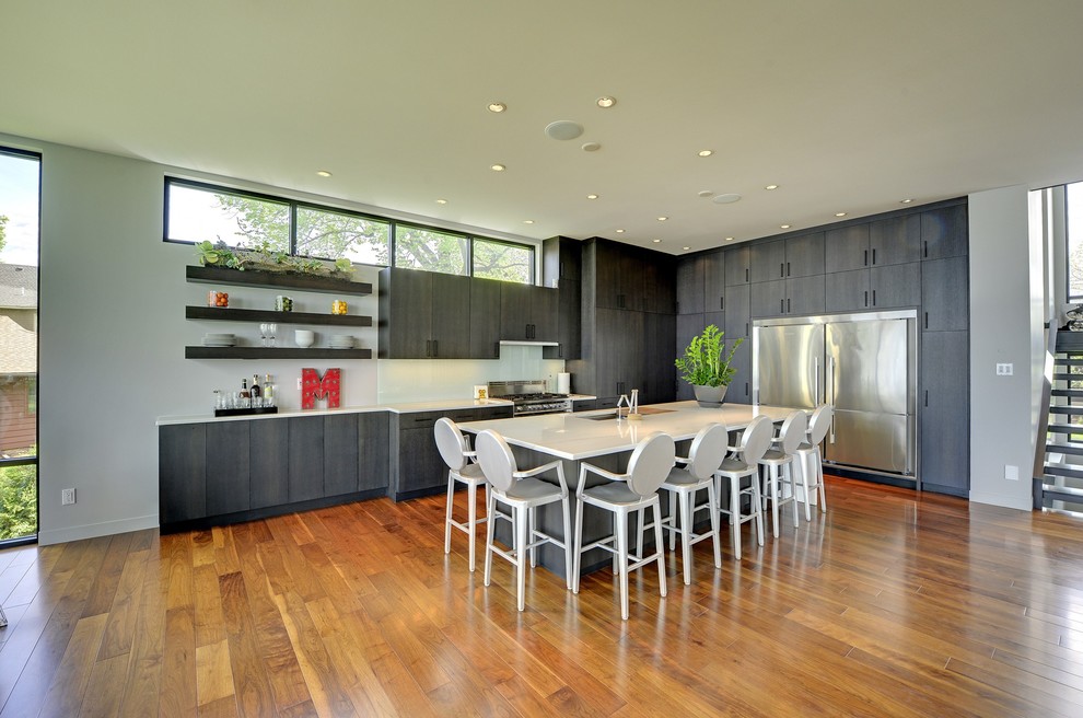 Contemporary l-shaped kitchen in Minneapolis with flat-panel cabinets, black cabinets, white splashback, glass sheet splashback and stainless steel appliances.