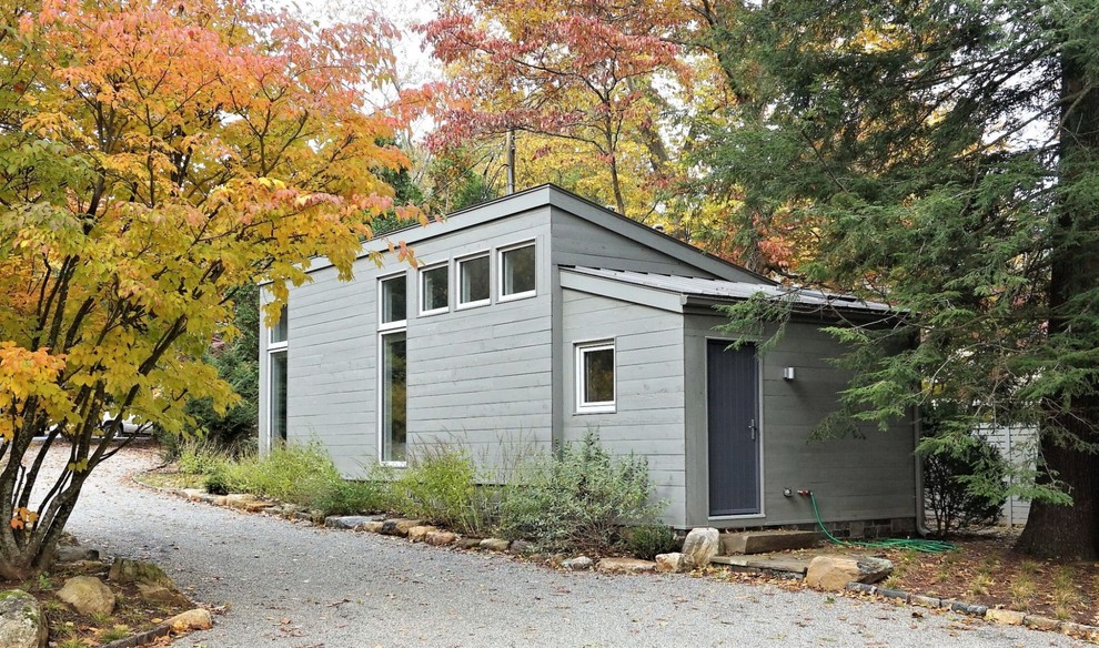Photo of a mid-sized contemporary one-storey grey house exterior in New York with wood siding, a shed roof and a metal roof.