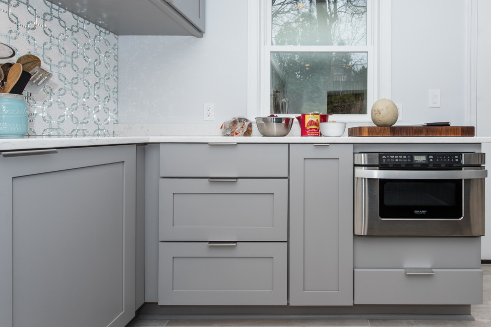 Design ideas for a mid-sized transitional l-shaped eat-in kitchen in DC Metro with an undermount sink, shaker cabinets, blue cabinets, glass benchtops, grey splashback, mosaic tile splashback, stainless steel appliances, porcelain floors and with island.