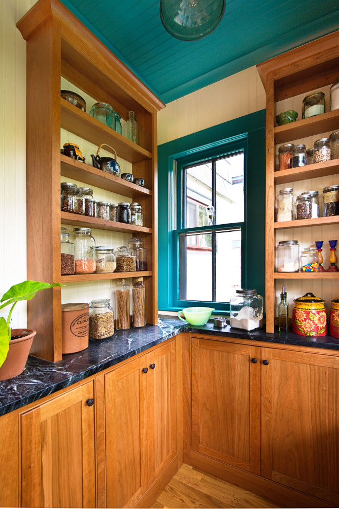 Photo of a mid-sized traditional l-shaped kitchen pantry in Minneapolis with a farmhouse sink, beaded inset cabinets, medium wood cabinets, soapstone benchtops, yellow splashback, timber splashback, stainless steel appliances, medium hardwood floors, brown floor, black benchtop and wood.
