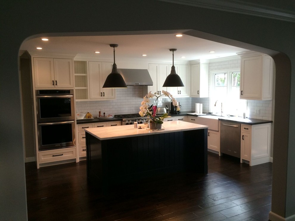 Mid-sized transitional l-shaped dark wood floor eat-in kitchen photo in San Francisco with a farmhouse sink, shaker cabinets, white cabinets, marble countertops, white backsplash, subway tile backsplash, stainless steel appliances and an island