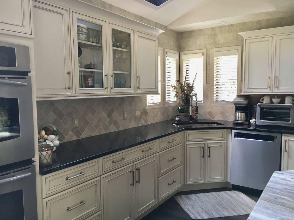 Eat-in kitchen - large transitional u-shaped laminate floor and gray floor eat-in kitchen idea with an undermount sink, recessed-panel cabinets, white cabinets, granite countertops, white backsplash, ceramic backsplash, stainless steel appliances, an island and black countertops