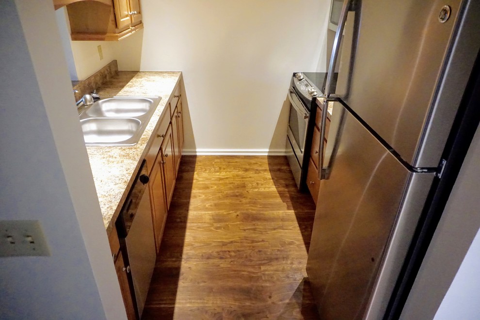 Enclosed kitchen - small transitional galley vinyl floor and brown floor enclosed kitchen idea with a double-bowl sink, raised-panel cabinets, medium tone wood cabinets, laminate countertops, beige backsplash, ceramic backsplash, stainless steel appliances and an island