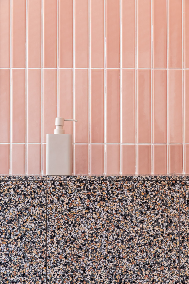 This is an example of a mid-sized scandinavian master bathroom in Sydney with a freestanding tub, an open shower, a two-piece toilet, pink tile, ceramic tile, terrazzo floors, a wall-mount sink, multi-coloured floor, an open shower, a single vanity, a floating vanity, medium wood cabinets, pink walls, wood benchtops and brown benchtops.