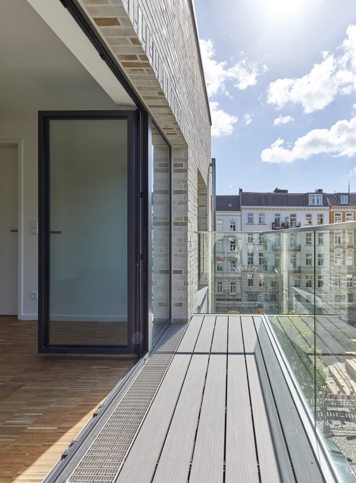 Large contemporary balcony in Hamburg with a container garden, no cover and glass railing.