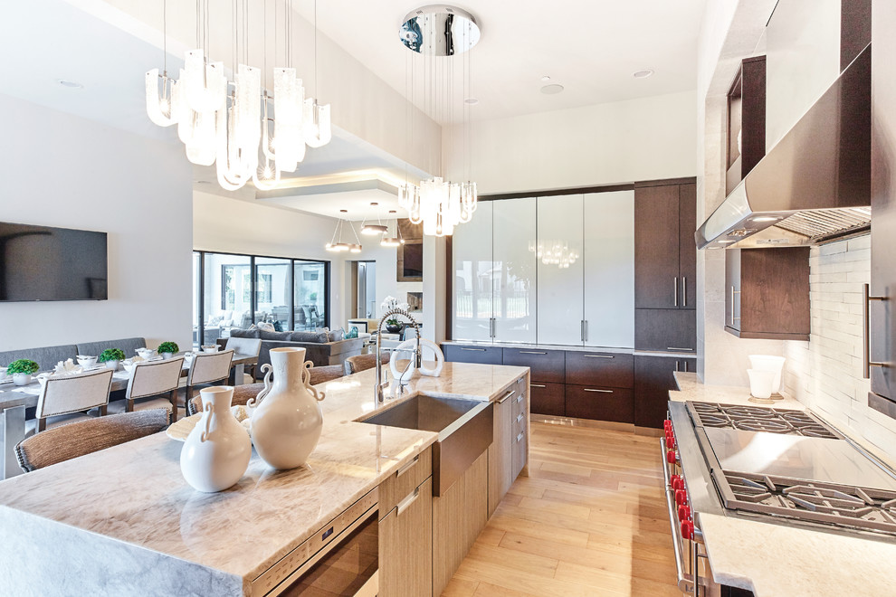Mid-sized contemporary single-wall eat-in kitchen in Dallas with a farmhouse sink, flat-panel cabinets, dark wood cabinets, granite benchtops, beige splashback, stainless steel appliances, light hardwood floors, with island, brown floor and beige benchtop.