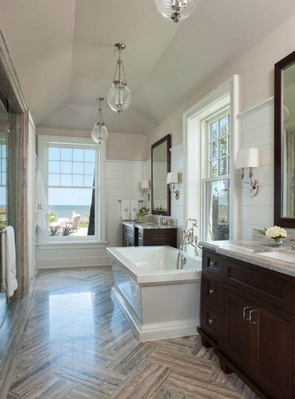 Inspiration for a mid-sized beach style master bathroom in Jacksonville with beaded inset cabinets, dark wood cabinets, a freestanding tub, gray tile, stone tile and limestone benchtops.