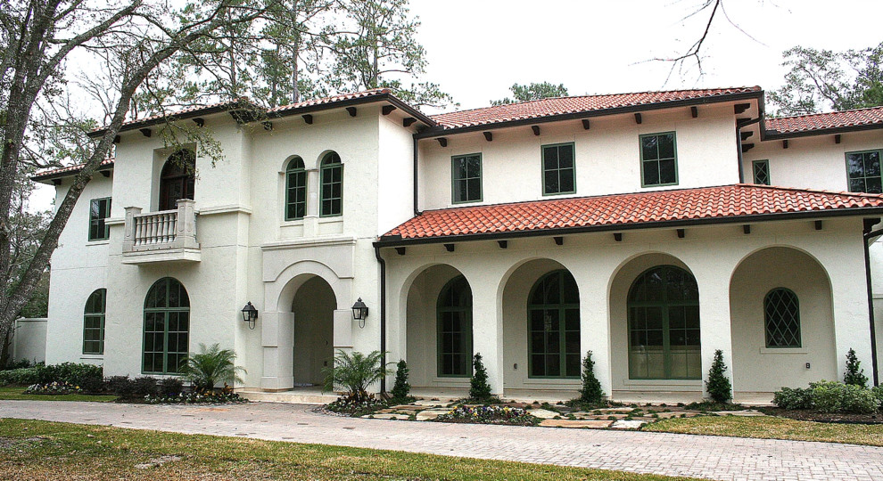 This is an example of a mid-sized mediterranean two-storey beige house exterior in Houston with stone veneer, a hip roof and a tile roof.