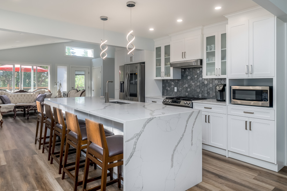 Inspiration for a transitional kitchen remodel in Edmonton with shaker cabinets, white cabinets, quartzite countertops, gray backsplash, cement tile backsplash, stainless steel appliances, an island and white countertops