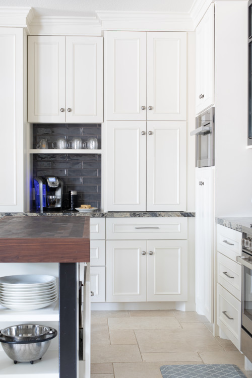 Tall white kitchen cabinets with built-in wall oven and coffee station niche beside the island