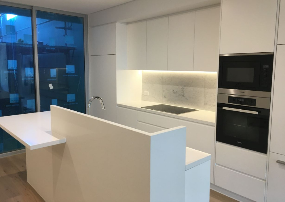 Design ideas for a small contemporary l-shaped eat-in kitchen in Sydney with an integrated sink, multi-coloured splashback, marble splashback, stainless steel appliances, with island and white benchtop.