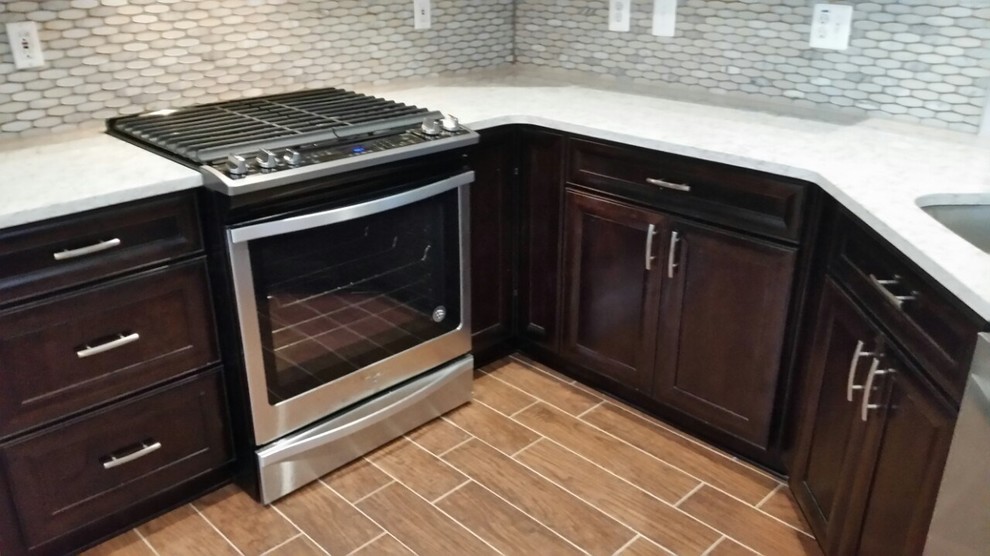 Mid-sized transitional l-shaped laminate floor and brown floor enclosed kitchen photo in DC Metro with an undermount sink, recessed-panel cabinets, dark wood cabinets, quartzite countertops, white backsplash, mosaic tile backsplash, stainless steel appliances, a peninsula and white countertops