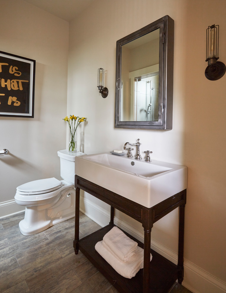 Mid-sized transitional 3/4 beige tile light wood floor corner bathtub photo with a one-piece toilet, beige walls and a trough sink