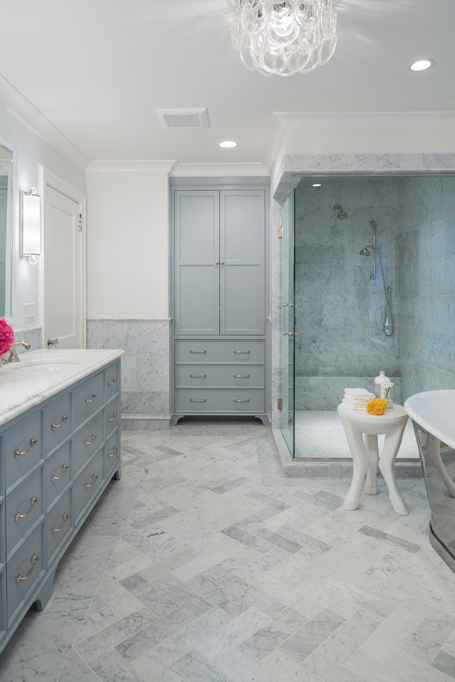 This is an example of a traditional master bathroom in Minneapolis with shaker cabinets, blue cabinets, a corner shower, multi-coloured tile, marble, white walls, an undermount sink, marble benchtops and a hinged shower door.