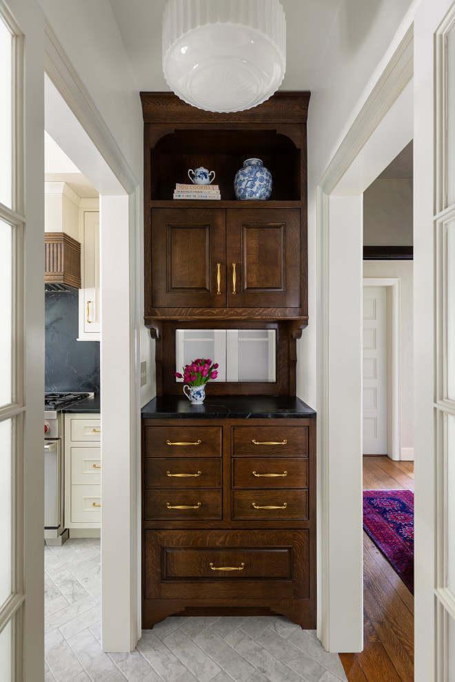 Mid-sized elegant beige floor home bar photo in Minneapolis with recessed-panel cabinets, white cabinets, soapstone countertops, black backsplash, stone slab backsplash and black countertops