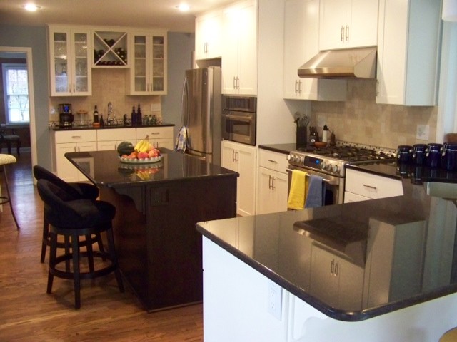 This is an example of a mid-sized traditional eat-in kitchen in Kansas City with an undermount sink, shaker cabinets, white cabinets, granite benchtops, beige splashback, porcelain splashback, stainless steel appliances, medium hardwood floors, with island and brown floor.