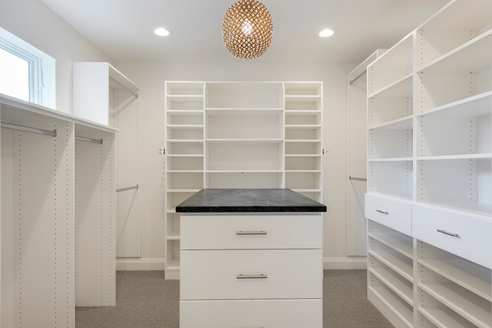 This is an example of a mid-sized transitional gender-neutral walk-in wardrobe in Minneapolis with flat-panel cabinets, white cabinets, carpet and grey floor.