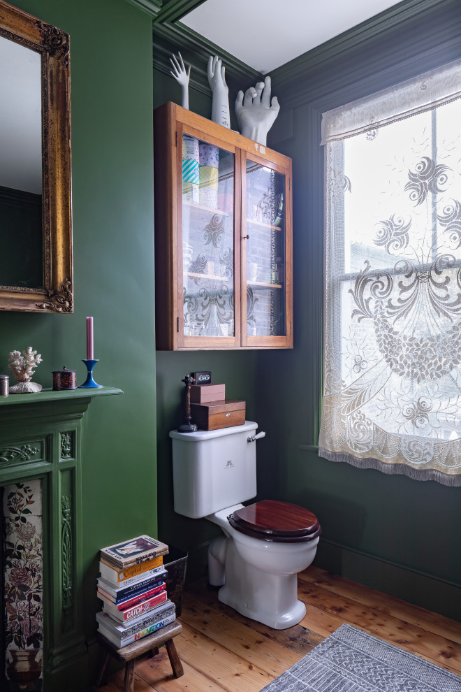 This is an example of a medium sized bohemian ensuite half tiled bathroom in London with a freestanding bath, a two-piece toilet, green tiles, medium hardwood flooring, brown floors, a chimney breast, a single sink and a floating vanity unit.