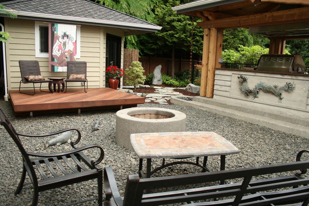 This is an example of a mid-sized asian backyard patio in Seattle with gravel, a gazebo/cabana and a fire feature.