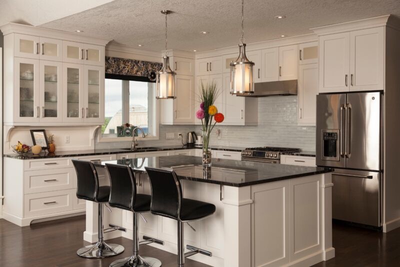 Transitional l-shaped dark wood floor open concept kitchen photo in Toronto with an undermount sink, shaker cabinets, white cabinets, marble countertops, blue backsplash, glass tile backsplash, stainless steel appliances and an island