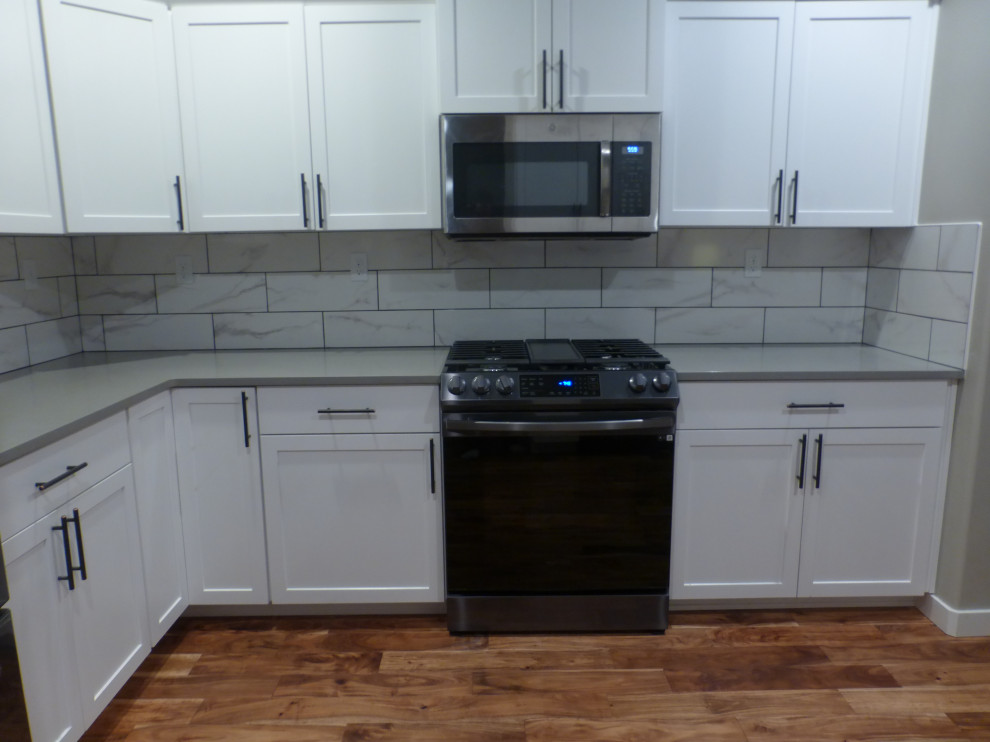Kitchen - mid-sized kitchen idea in Boise with white cabinets, quartz countertops, white backsplash, porcelain backsplash and gray countertops