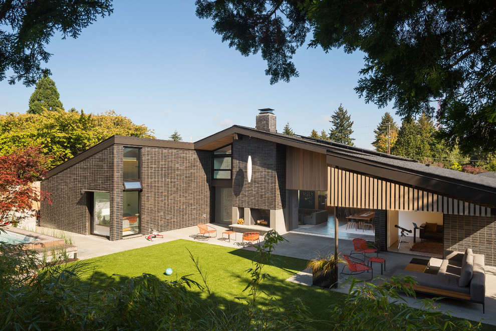 Photo of a large midcentury two-storey brick black exterior in Seattle with a gable roof.