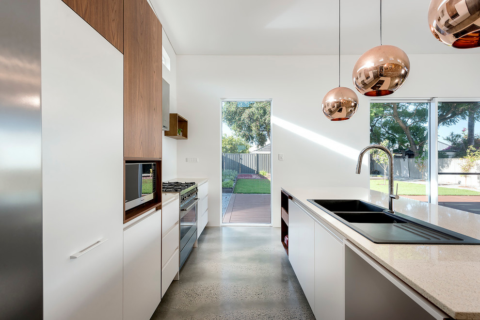 Photo of a small contemporary galley eat-in kitchen in Perth with an undermount sink, open cabinets, medium wood cabinets, quartz benchtops, white splashback, glass sheet splashback, stainless steel appliances, concrete floors and with island.