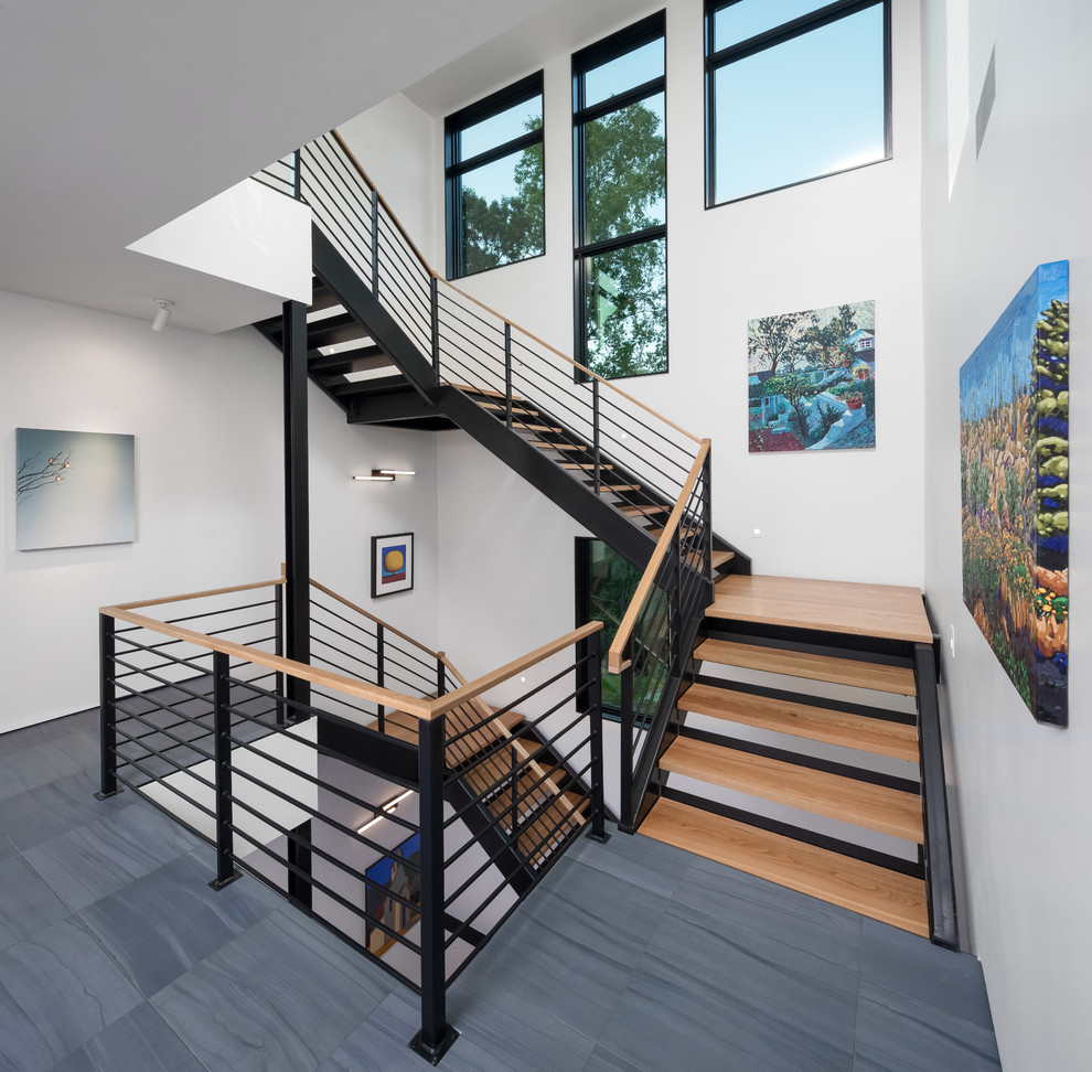 Design ideas for a large contemporary wood u-shaped staircase in Minneapolis with open risers and metal railing.