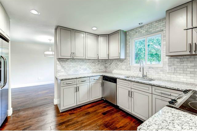 Inspiration for a mid-sized transitional u-shaped eat-in kitchen in Denver with an undermount sink, beaded inset cabinets, granite benchtops, stainless steel appliances, dark hardwood floors, no island, white cabinets, white splashback, subway tile splashback and brown floor.