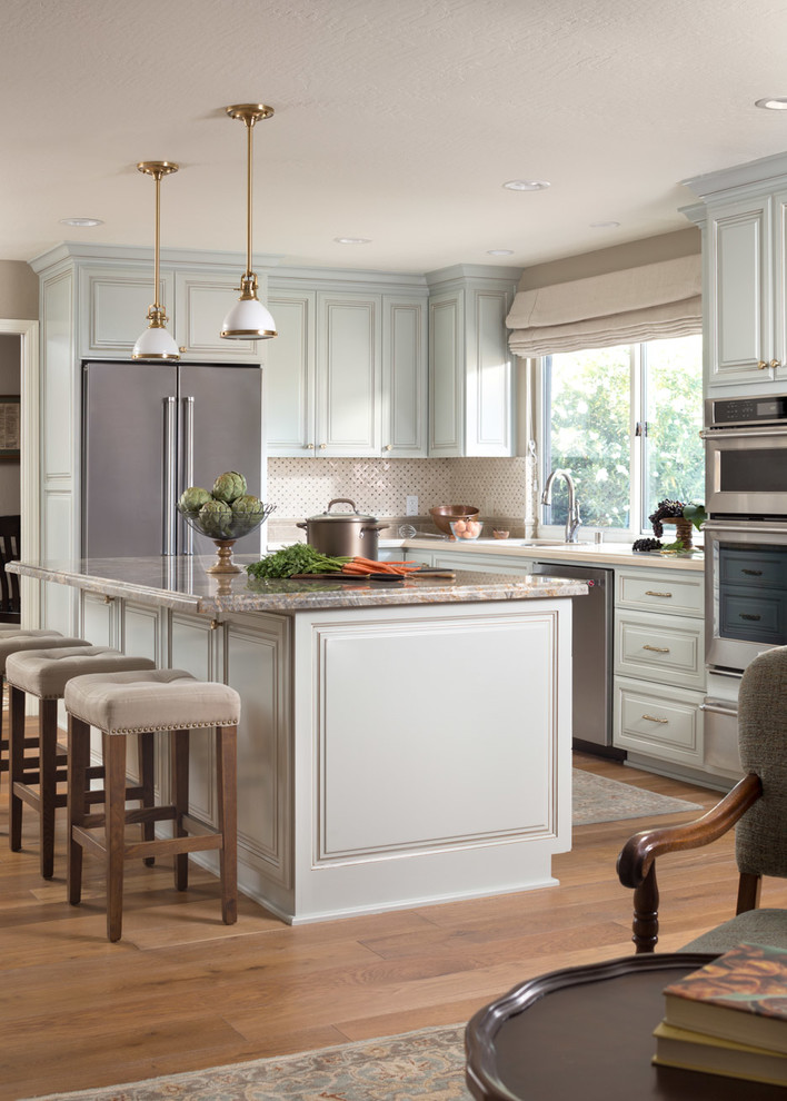 Inspiration for a traditional l-shaped open plan kitchen in San Francisco with raised-panel cabinets, green cabinets, stainless steel appliances, medium hardwood floors, with island, brown floor and grey benchtop.