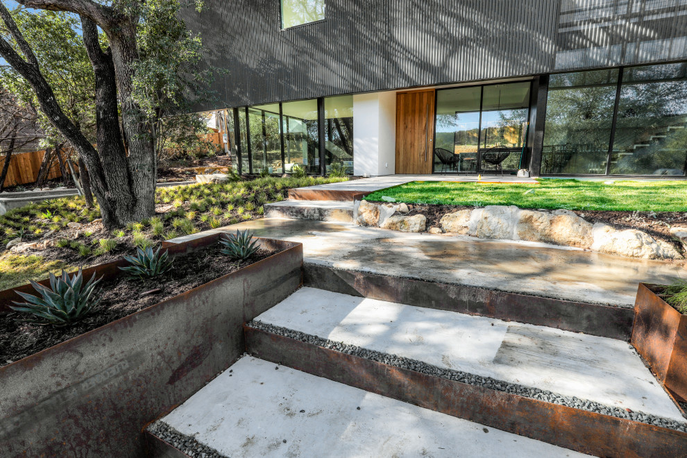 Expansive contemporary front yard partial sun driveway in Austin with with path and concrete pavers.