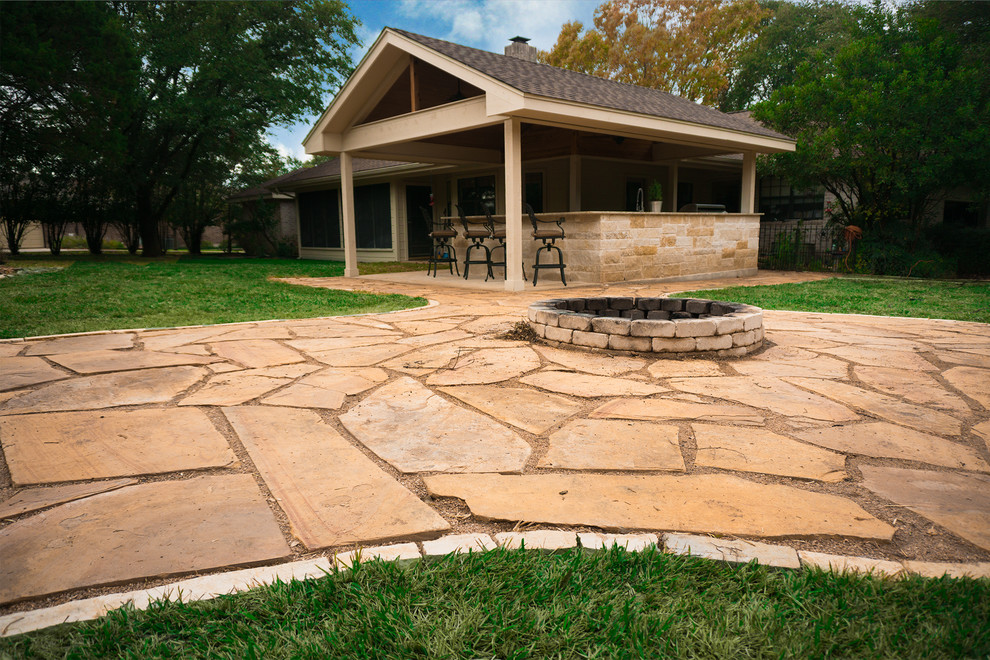Design ideas for a large traditional backyard patio in Austin with an outdoor kitchen, natural stone pavers and a roof extension.