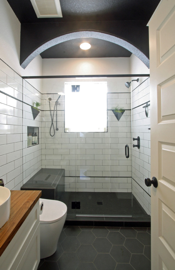 Small industrial bathroom in Portland with shaker cabinets, white cabinets, an alcove shower, a one-piece toilet, white tile, subway tile, white walls, porcelain floors, a vessel sink, wood benchtops, black floor, a hinged shower door, brown benchtops, a shower seat, a single vanity, a floating vanity and decorative wall panelling.