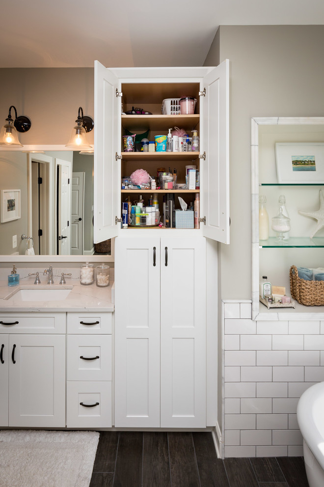 Inspiration for a large traditional master bathroom in DC Metro with shaker cabinets, white cabinets, a freestanding tub, an alcove shower, white tile, subway tile, grey walls, dark hardwood floors, an undermount sink, engineered quartz benchtops, brown floor, a hinged shower door and grey benchtops.