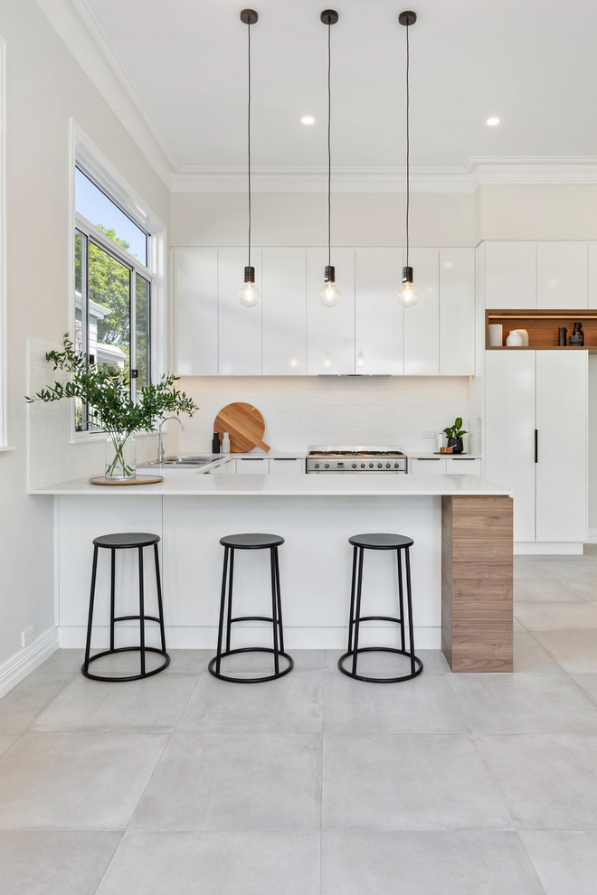 Inspiration for a contemporary u-shaped kitchen in Perth with a drop-in sink, flat-panel cabinets, white cabinets, white splashback, stainless steel appliances, a peninsula, grey floor and white benchtop.