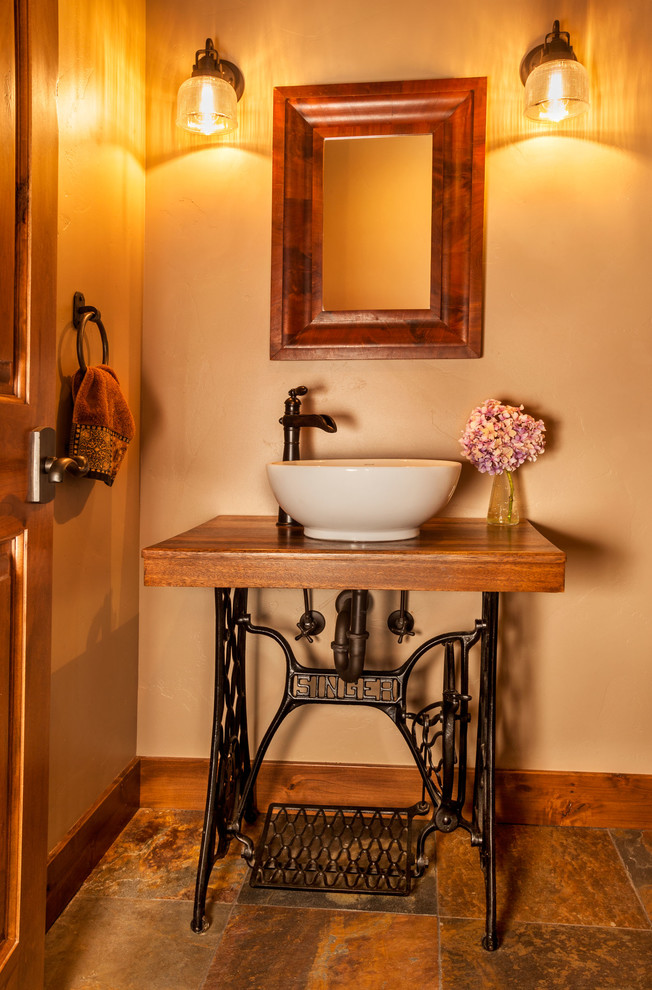 Design ideas for a small country powder room in Other with open cabinets, black cabinets, beige walls, slate floors, a vessel sink, wood benchtops, brown floor and brown benchtops.