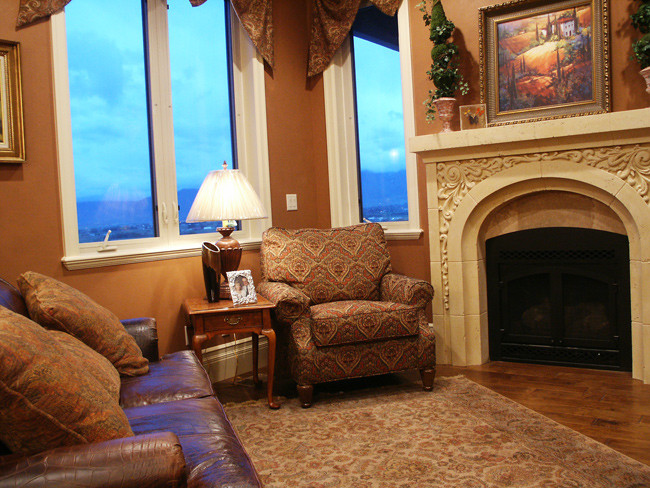 This is an example of a small traditional formal enclosed living room in Salt Lake City with brown walls, medium hardwood floors, a corner fireplace, a stone fireplace surround and no tv.