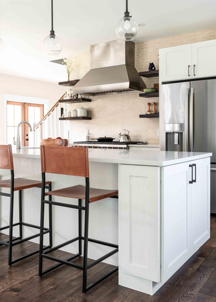 Inspiration for a mid-sized timeless l-shaped dark wood floor open concept kitchen remodel in Portland Maine with a farmhouse sink, shaker cabinets, white cabinets, quartz countertops, beige backsplash, ceramic backsplash, stainless steel appliances, an island and white countertops