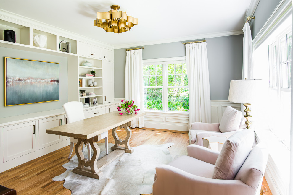 This is an example of a transitional study room in Boston with grey walls, medium hardwood floors, no fireplace, a freestanding desk, brown floor, panelled walls and decorative wall panelling.