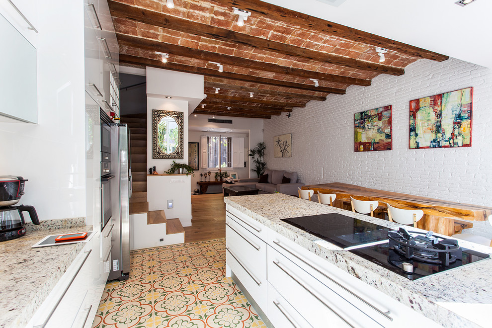 Photo of a large industrial single-wall open plan kitchen in Barcelona with granite benchtops, white splashback, stainless steel appliances, open cabinets, white cabinets, cement tiles, with island and beige floor.