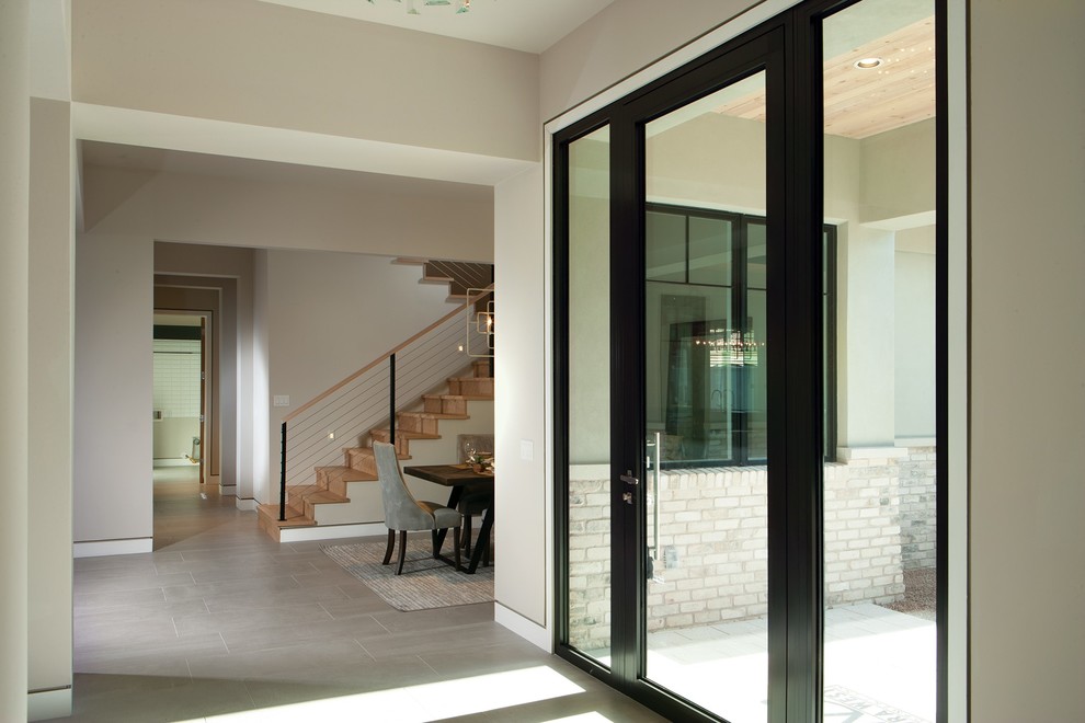 This is an example of a mid-sized contemporary front door in Phoenix with grey walls, porcelain floors, a pivot front door, a glass front door and grey floor.